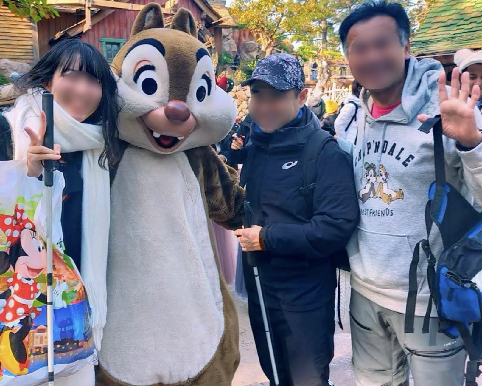 ディズニーランドでチップと写真を撮る白杖を持ったカップルとガイド